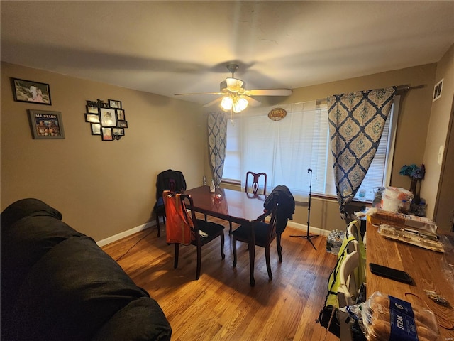 dining space featuring a ceiling fan, visible vents, baseboards, and wood finished floors