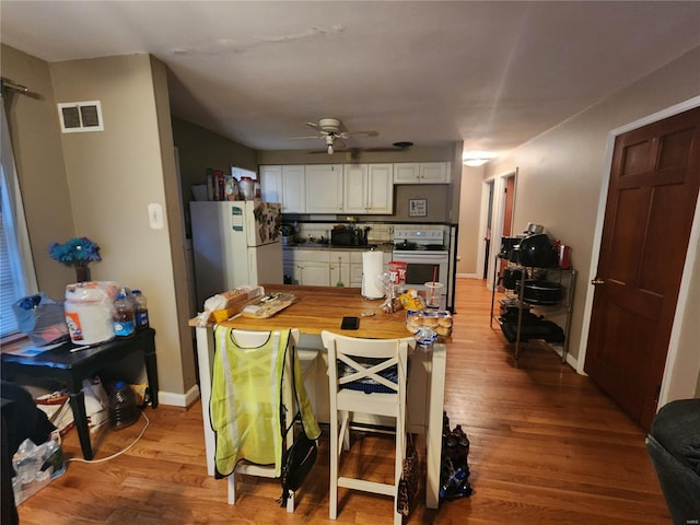 kitchen featuring wood finished floors, visible vents, white cabinets, freestanding refrigerator, and stainless steel electric range oven