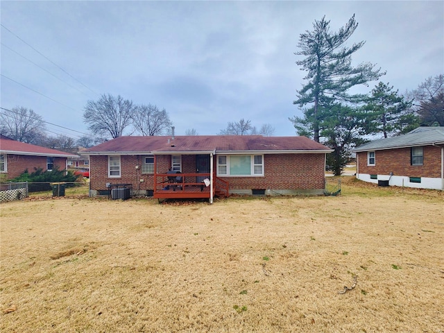 back of property with brick siding, a lawn, central AC, fence, and a deck