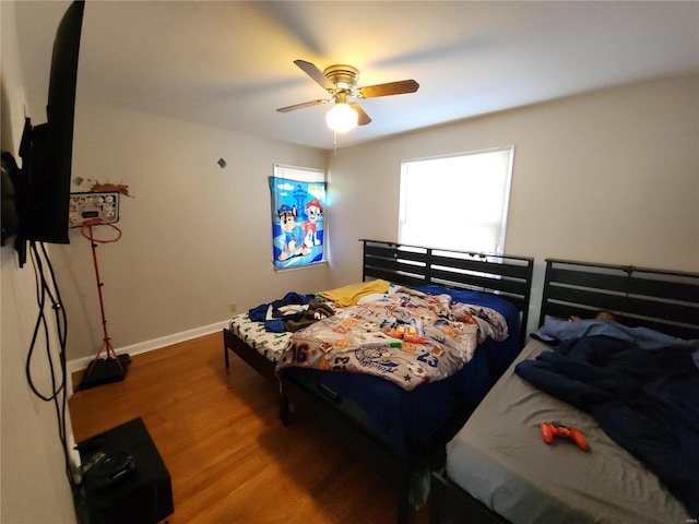 bedroom with a ceiling fan, baseboards, and wood finished floors