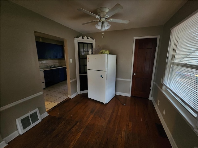 kitchen featuring blue cabinetry, white refrigerator, dark hardwood / wood-style floors, ceiling fan, and backsplash