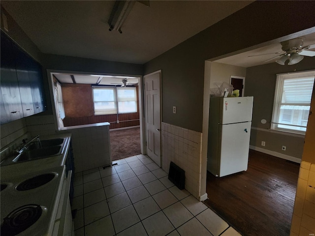 kitchen featuring ceiling fan, sink, white fridge, and tile walls