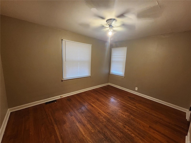 empty room featuring baseboards, dark wood finished floors, and a ceiling fan