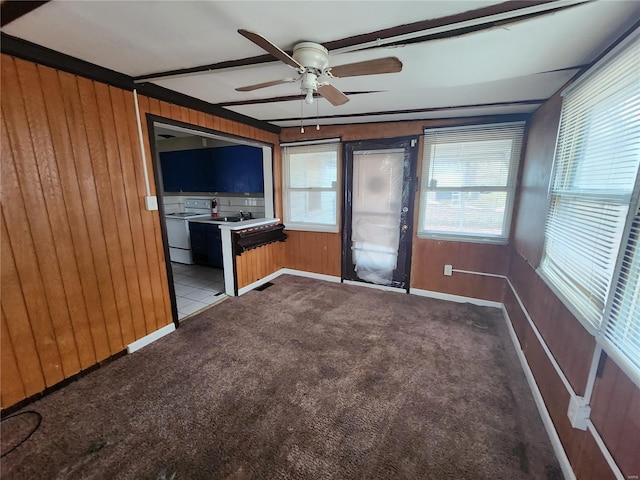 unfurnished living room featuring carpet floors, a ceiling fan, and wooden walls