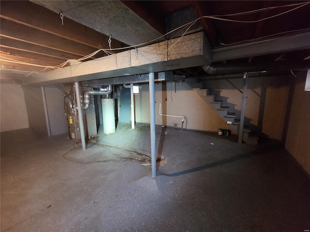 unfinished below grade area featuring heating unit, stairs, and gas water heater