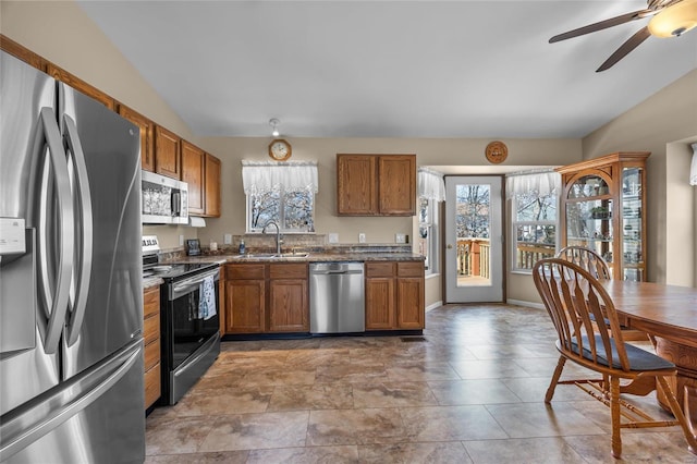 kitchen featuring a sink, lofted ceiling, appliances with stainless steel finishes, and brown cabinetry