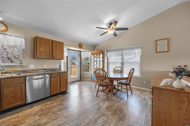 kitchen with baseboards, a sink, vaulted ceiling, stainless steel dishwasher, and brown cabinets