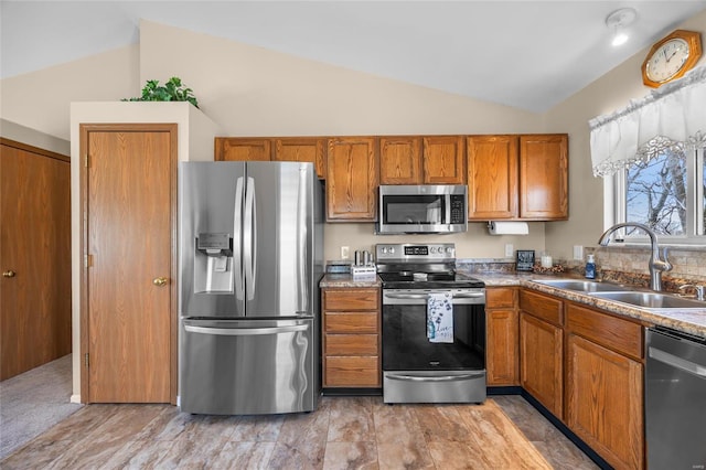 kitchen with vaulted ceiling, brown cabinets, stainless steel appliances, and a sink