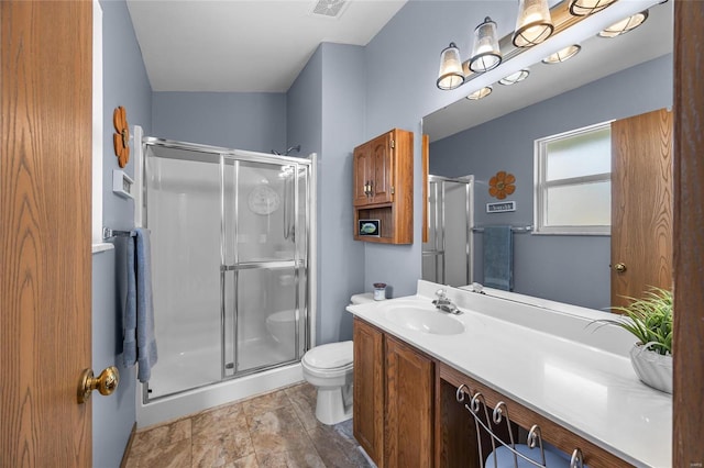 bathroom with visible vents, a shower stall, toilet, and vanity