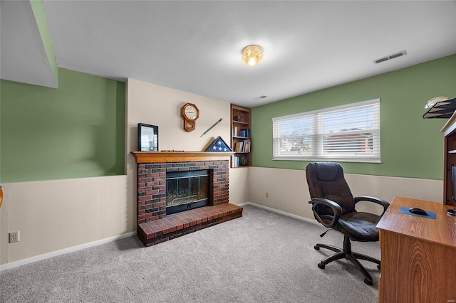 carpeted office with visible vents, baseboards, and a fireplace