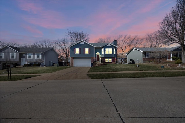 split foyer home with a yard, brick siding, concrete driveway, and an attached garage