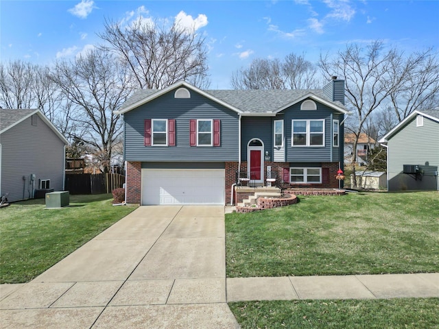 bi-level home with a front lawn, concrete driveway, an attached garage, brick siding, and a chimney