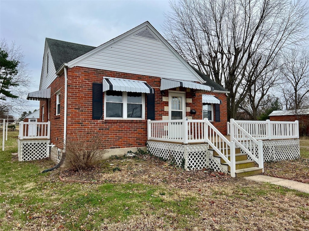 bungalow with a wooden deck and a front yard