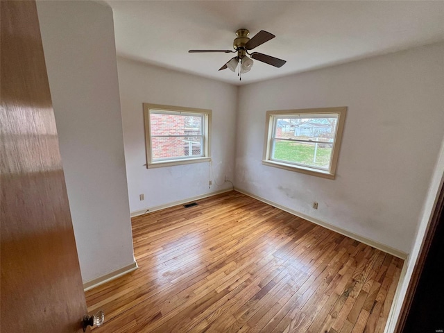 unfurnished room with a wealth of natural light, ceiling fan, and light wood-type flooring