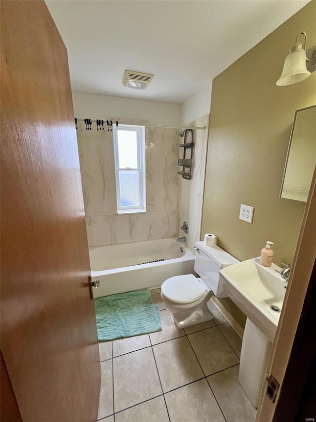 bathroom featuring tile patterned flooring, tiled shower / bath combo, and toilet