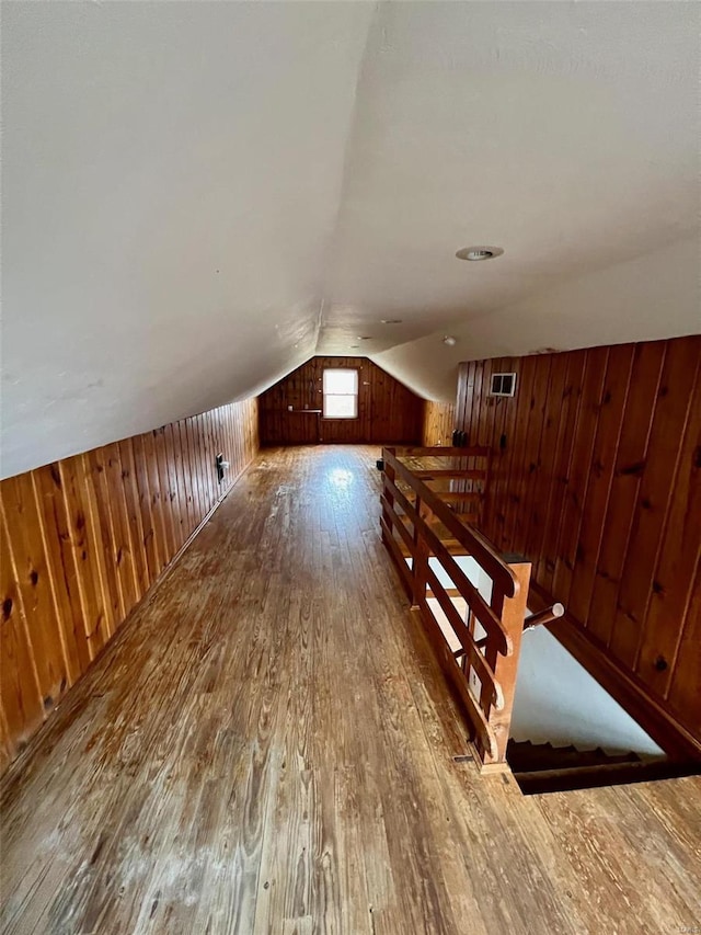 bonus room with hardwood / wood-style flooring, wooden walls, and vaulted ceiling