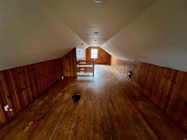 bonus room featuring wooden walls, dark wood-type flooring, and lofted ceiling