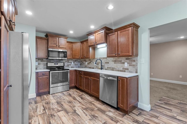 kitchen with backsplash, sink, light wood-type flooring, and stainless steel appliances