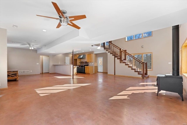 unfurnished living room with ceiling fan and a wood stove