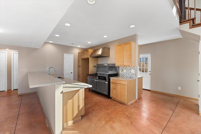 kitchen featuring wall chimney range hood, sink, an island with sink, and light brown cabinets