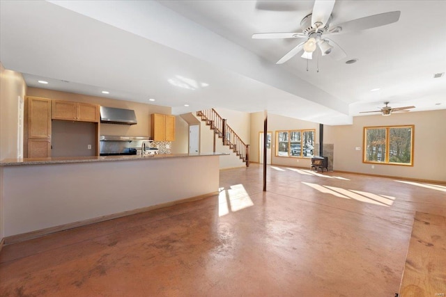 interior space with ceiling fan, sink, and a wood stove