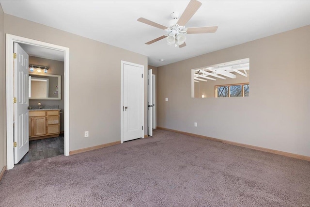 unfurnished bedroom featuring ceiling fan, ensuite bath, and dark colored carpet