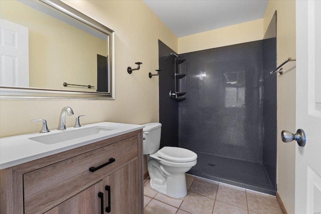 bathroom featuring tile patterned floors, toilet, vanity, and a shower