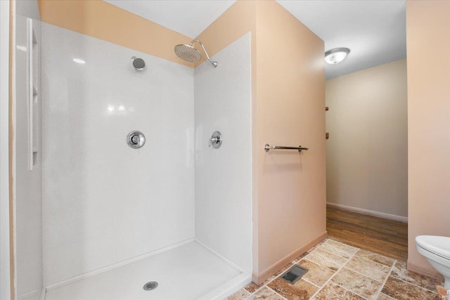 bathroom featuring walk in shower and toilet