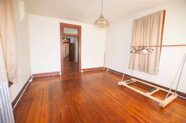 unfurnished room with hardwood / wood-style floors and an inviting chandelier