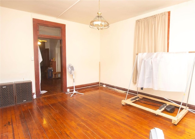 empty room with ceiling fan with notable chandelier and dark hardwood / wood-style flooring