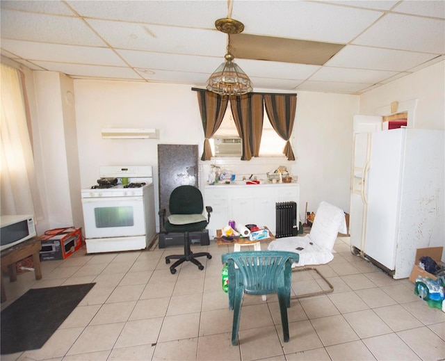 kitchen with a paneled ceiling, pendant lighting, white appliances, sink, and light tile patterned floors