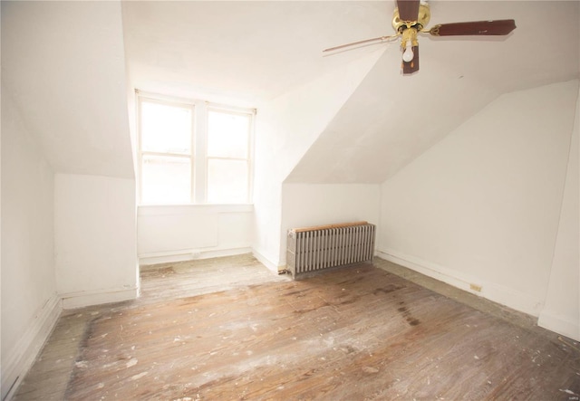 additional living space with ceiling fan, radiator heating unit, wood-type flooring, and lofted ceiling