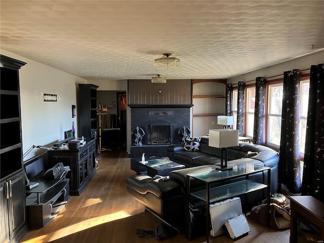 living room with a textured ceiling, hardwood / wood-style flooring, and a brick fireplace