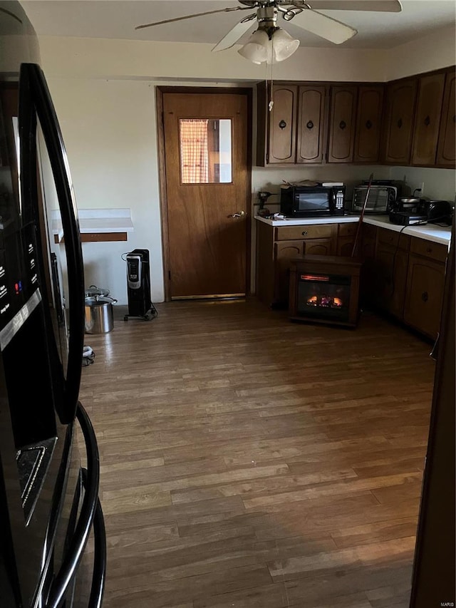 kitchen featuring black appliances, ceiling fan, dark brown cabinetry, and hardwood / wood-style floors