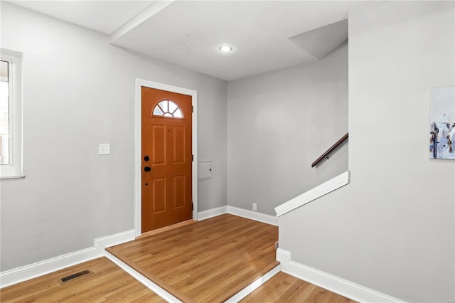 foyer with visible vents, stairway, baseboards, and wood finished floors