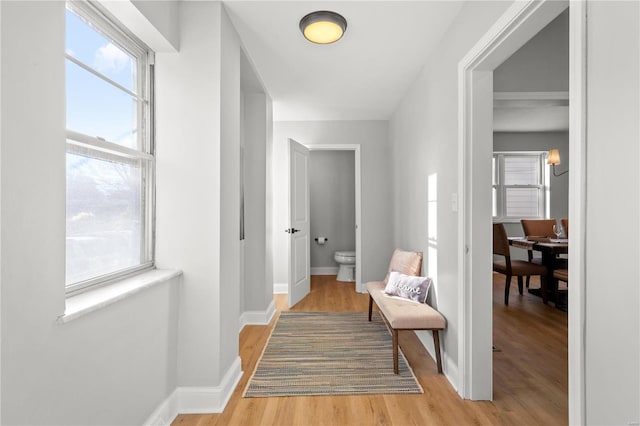 corridor with light wood-type flooring and baseboards