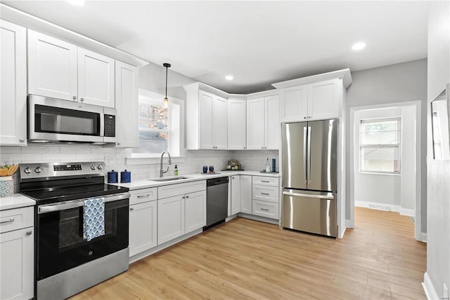 kitchen with decorative backsplash, appliances with stainless steel finishes, light countertops, white cabinetry, and a sink