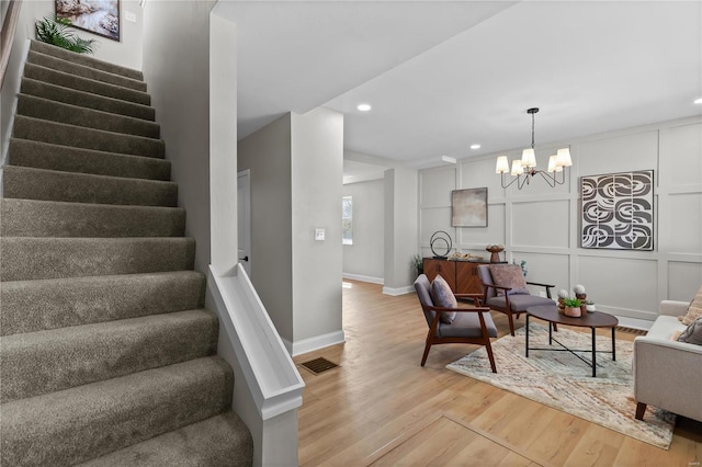 living area with stairway, light wood-style flooring, a notable chandelier, visible vents, and recessed lighting