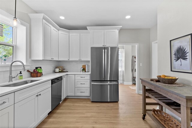 kitchen with appliances with stainless steel finishes, a sink, white cabinetry, and light countertops
