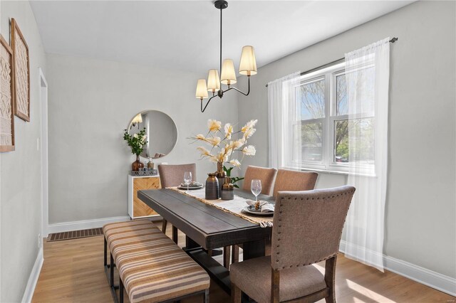 dining space featuring visible vents, baseboards, wood finished floors, and a chandelier