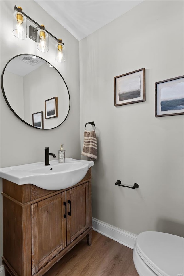 bathroom featuring wood finished floors, baseboards, vanity, and toilet