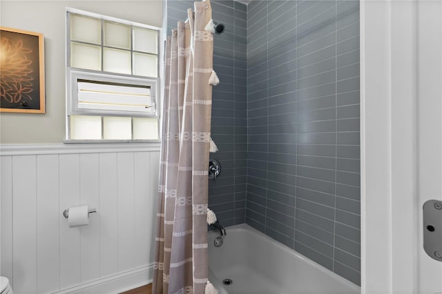 bathroom with shower / bath combo with shower curtain and a wainscoted wall