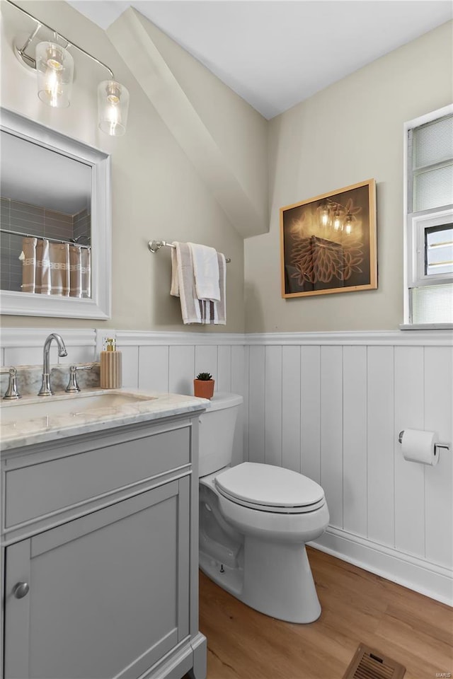 full bathroom with toilet, wainscoting, visible vents, wood finished floors, and vanity
