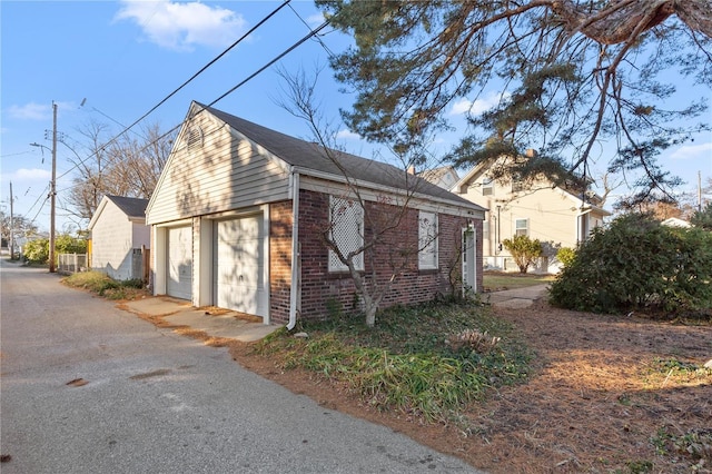 view of side of property with an outdoor structure, brick siding, and a garage