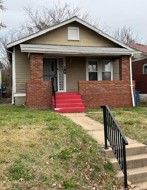 bungalow featuring covered porch and a front lawn