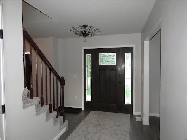 foyer entrance with dark wood-type flooring and a notable chandelier