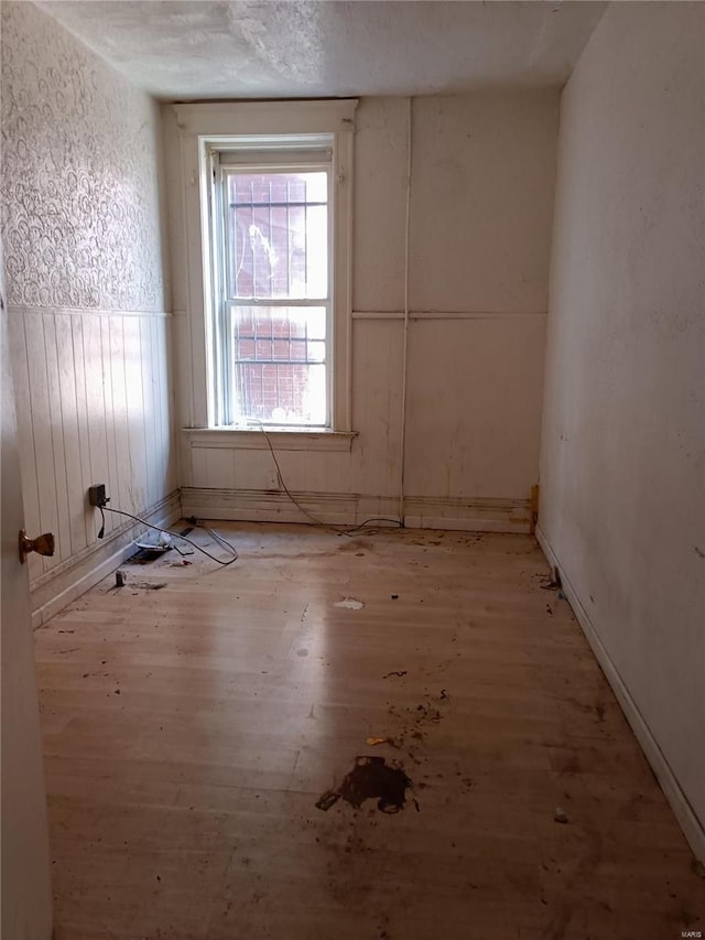 spare room featuring a textured ceiling and light hardwood / wood-style floors