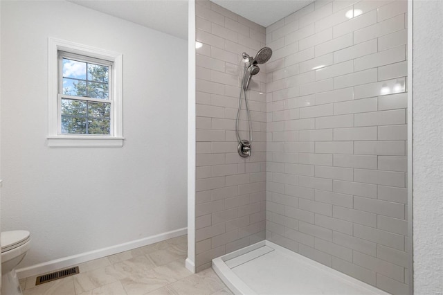 bathroom featuring a tile shower and toilet