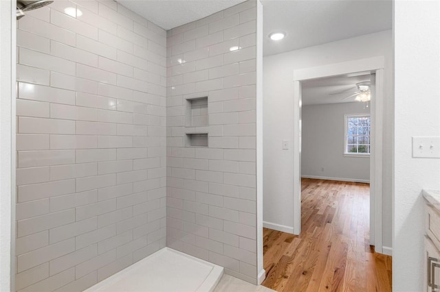 bathroom featuring hardwood / wood-style flooring, vanity, ceiling fan, and tiled shower