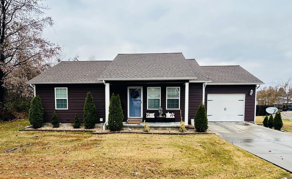 single story home with covered porch, a garage, and a front lawn